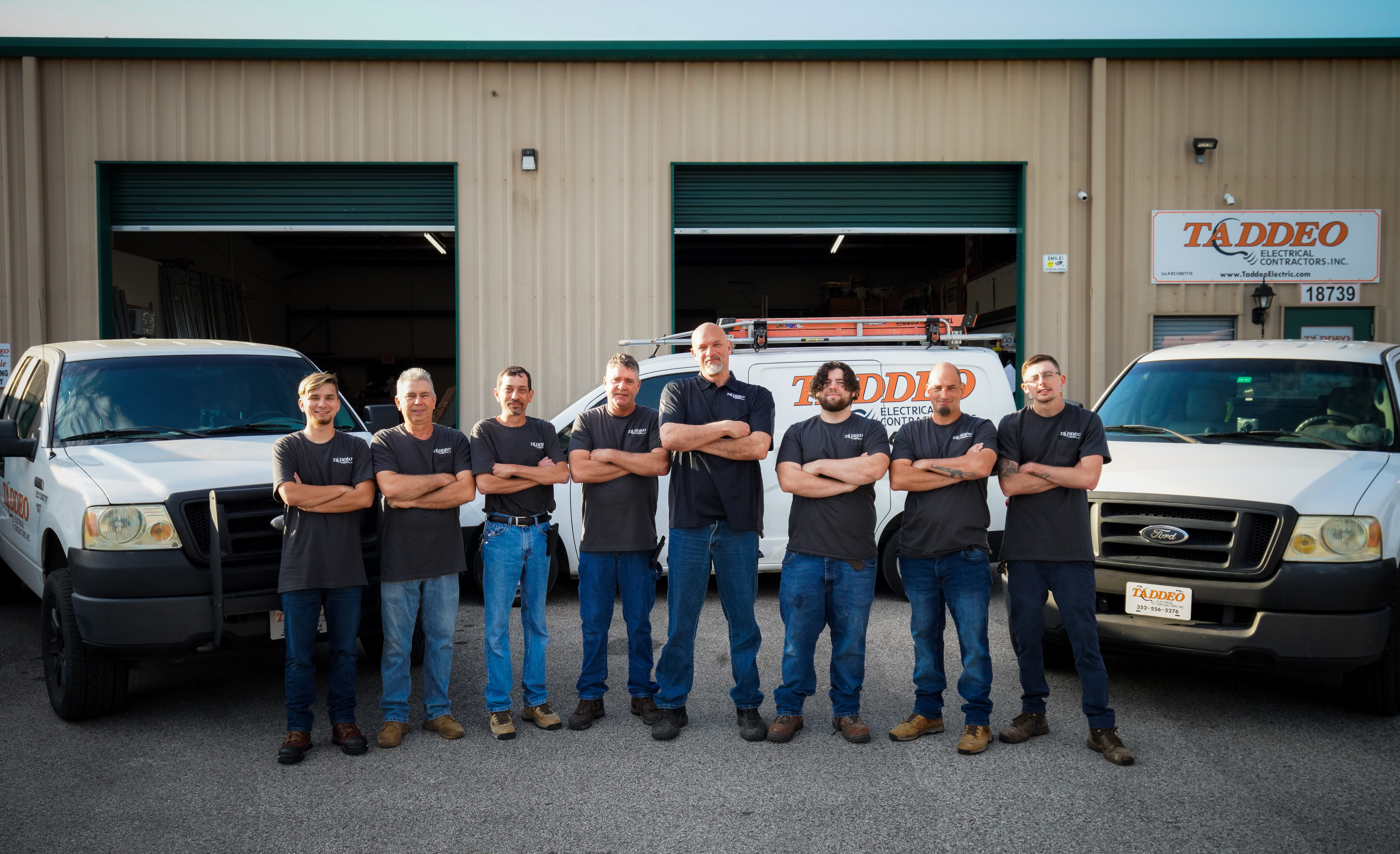 Taddeo electrician team standing in front of their service vehicles