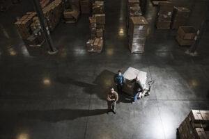 A group of three warehouse workers standing in the center of a distribution warehouse.