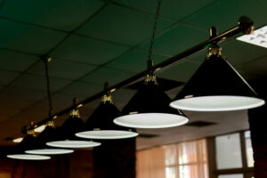 Row of Billiard lamps above a table in dark in pub.